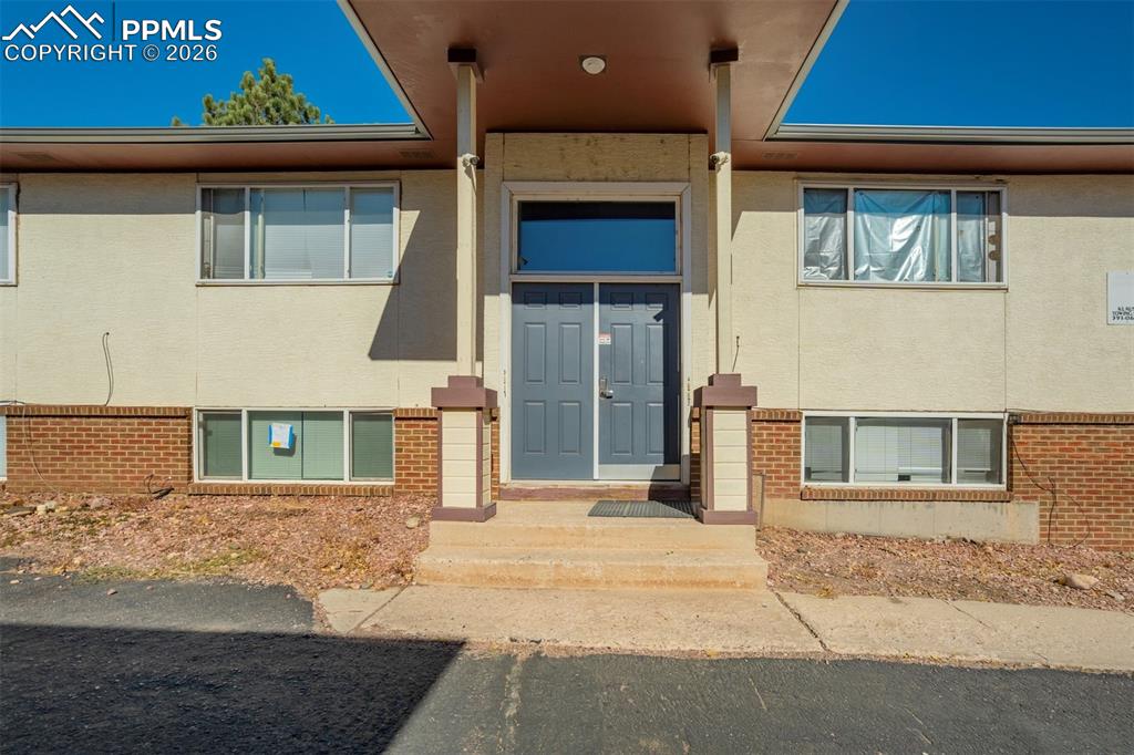 Image 3 of 42: Doorway to property featuring brick siding and stucco siding