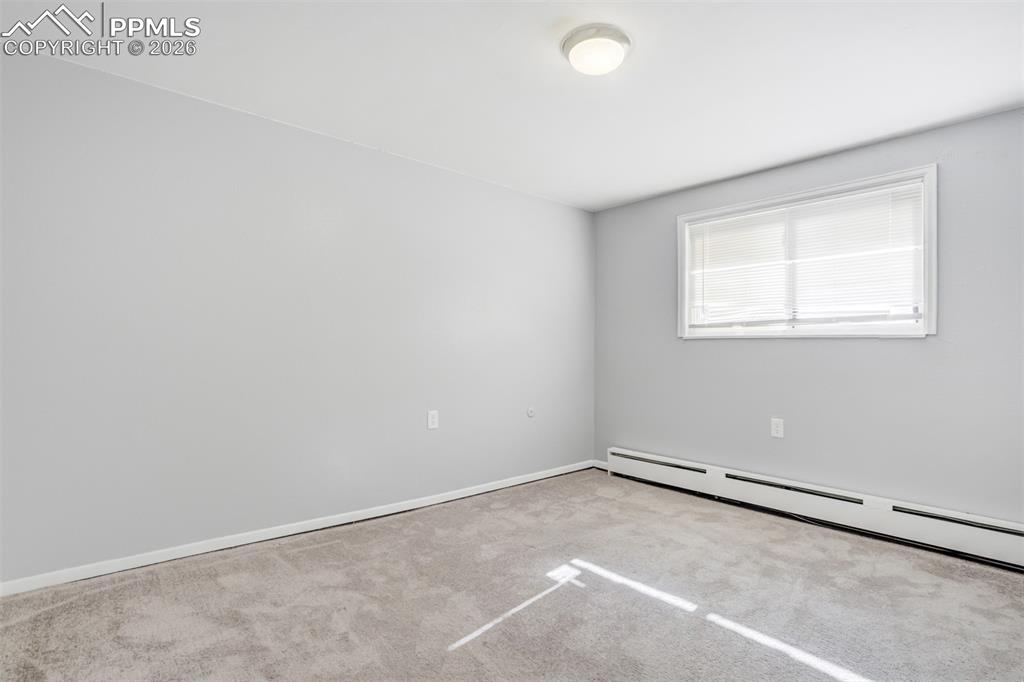 Image 33 of 42: Empty room with light carpet and a baseboard heating unit