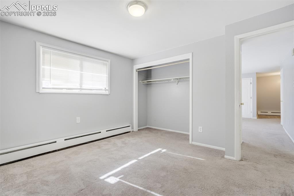 Image 34 of 42: Unfurnished bedroom featuring carpet flooring, baseboard heating, and a clo