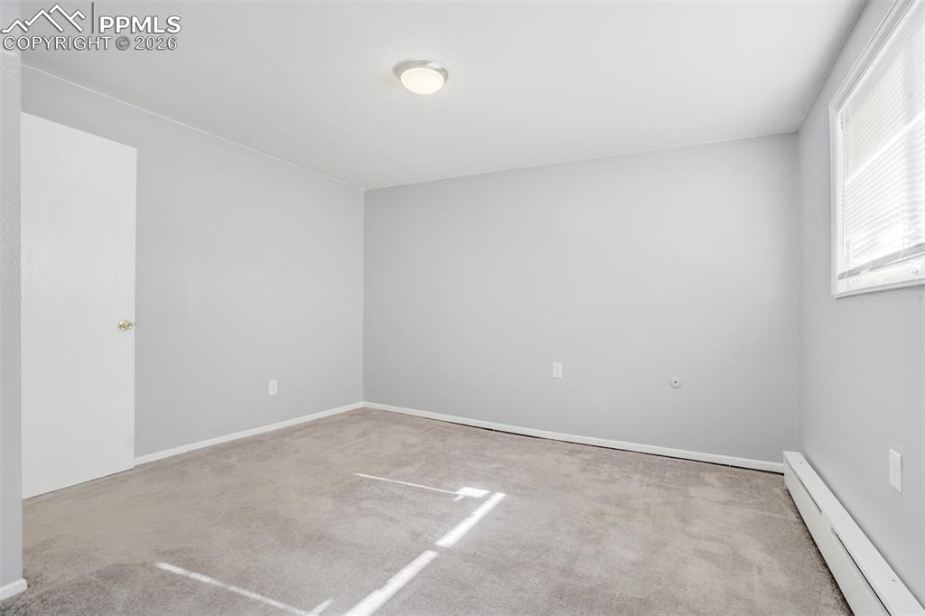 Image 36 of 42: Spare room featuring baseboard heating and light carpet