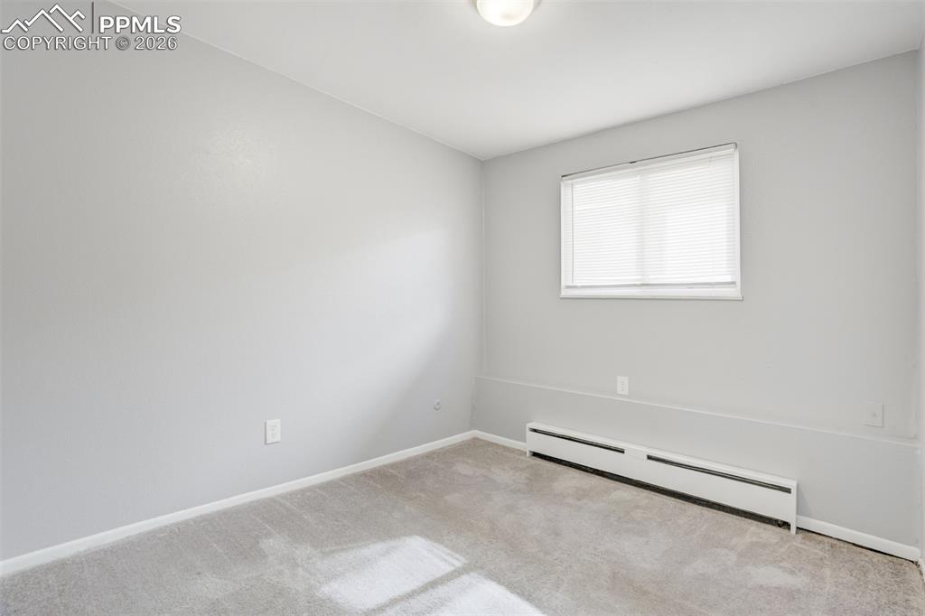 Image 39 of 42: Spare room featuring baseboard heating and light carpet