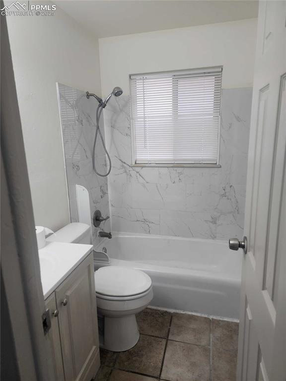 Image 4 of 13: Bathroom featuring washtub / shower combination, vanity, and dark tile patt