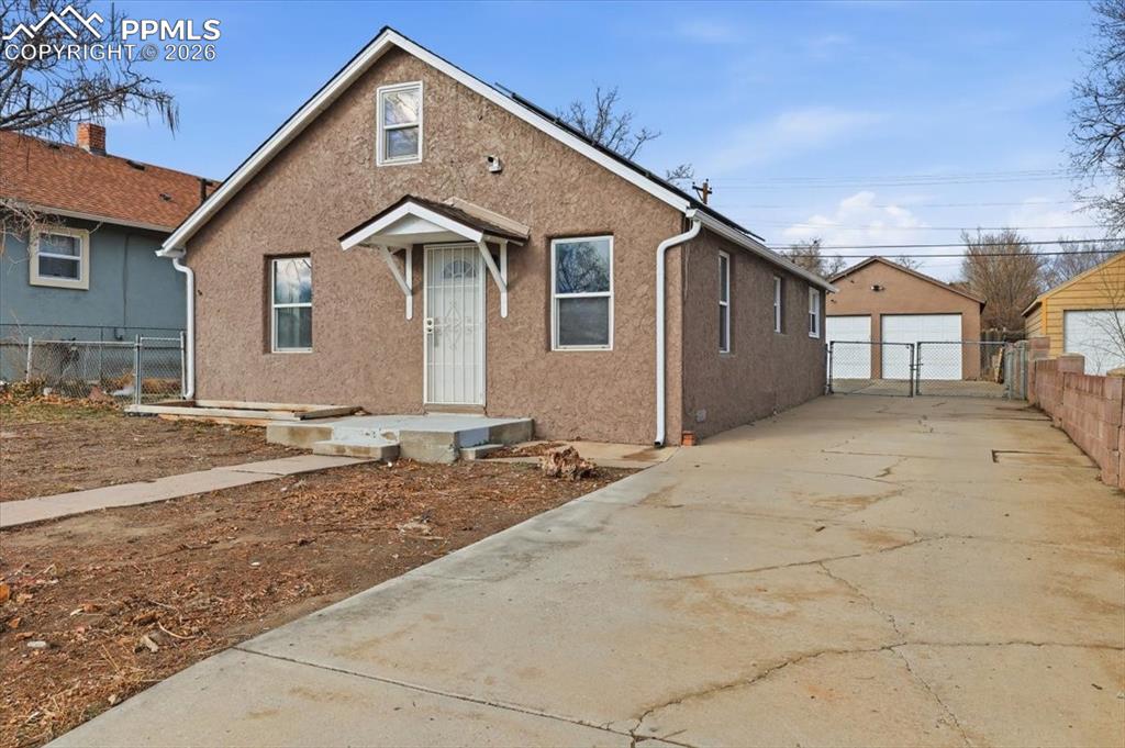 Image 1 of 24: Bungalow featuring an outbuilding, a detached garage, and stucco siding
