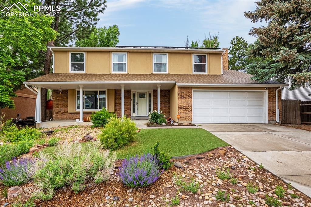 Caption: Traditional-style home with driveway, a porch, stucco siding, and brick siding