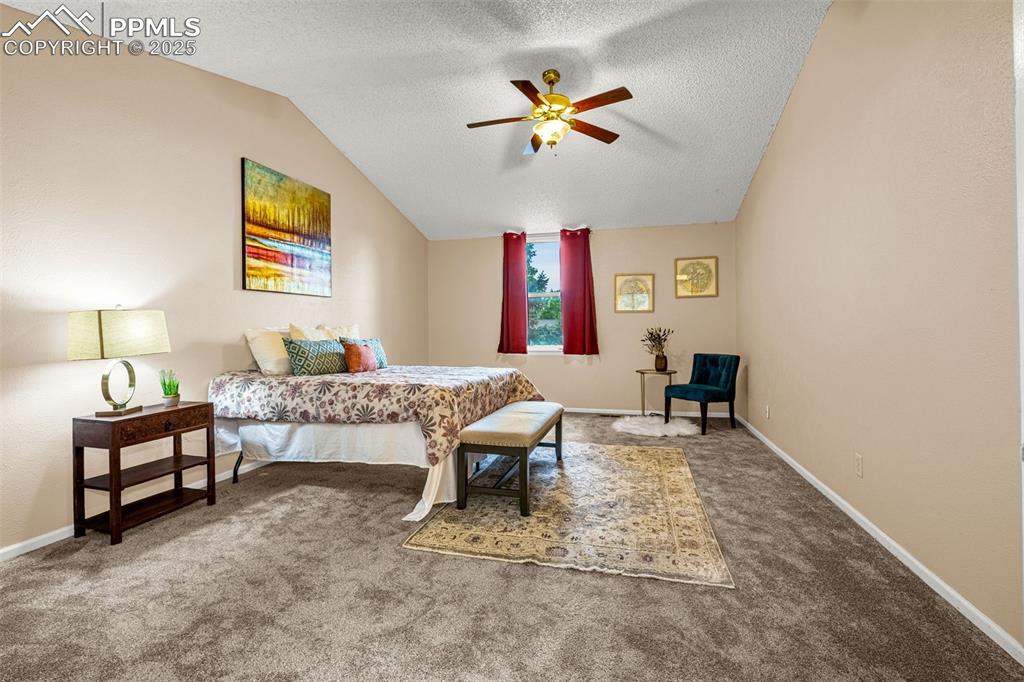 Image 13 of 38: Bedroom with lofted ceiling, carpet flooring, a textured ceiling, baseboard