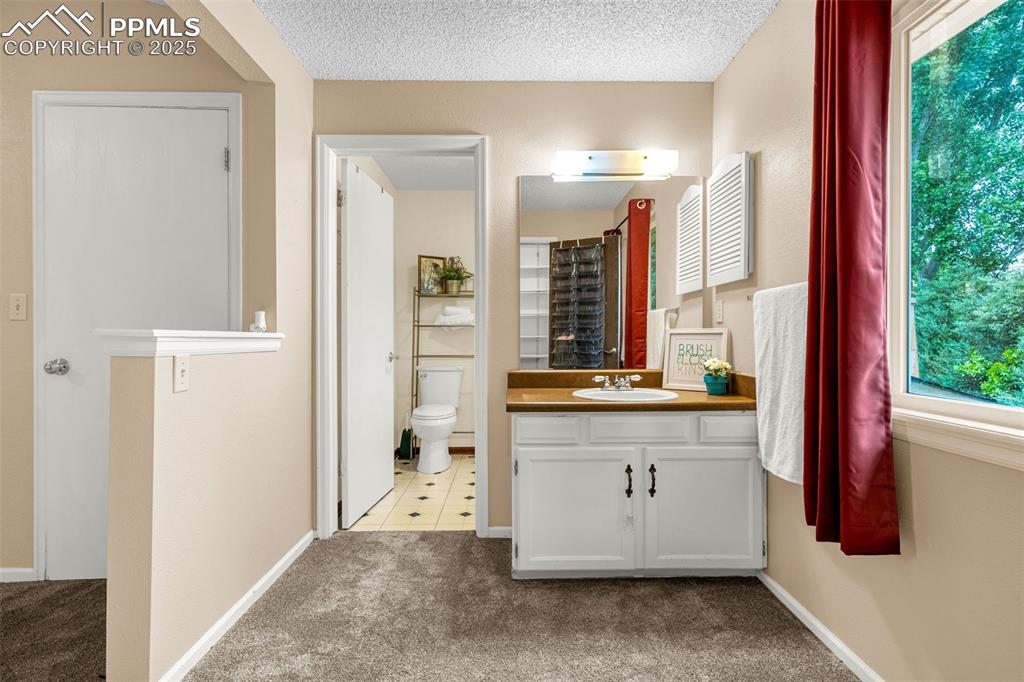Image 17 of 38: Full bathroom featuring toilet, vanity, curtained shower, and baseboards