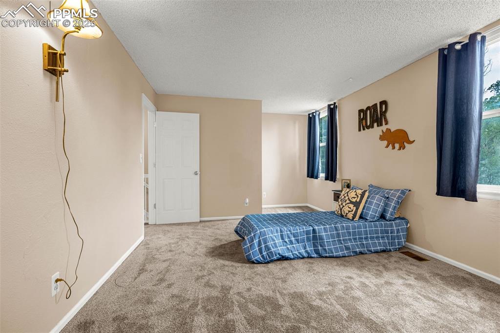 Image 19 of 38: Bedroom with carpet floors, a textured ceiling, and baseboards