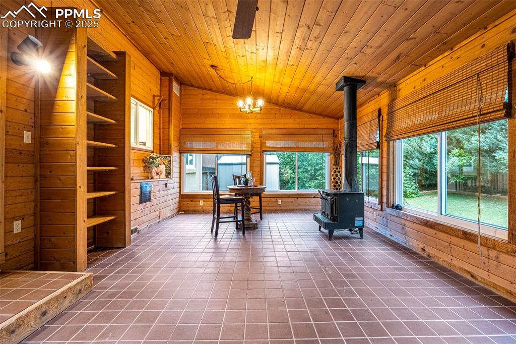 Image 27 of 38: Sunroom with a wood stove, vaulted ceiling, plenty of natural light, and a