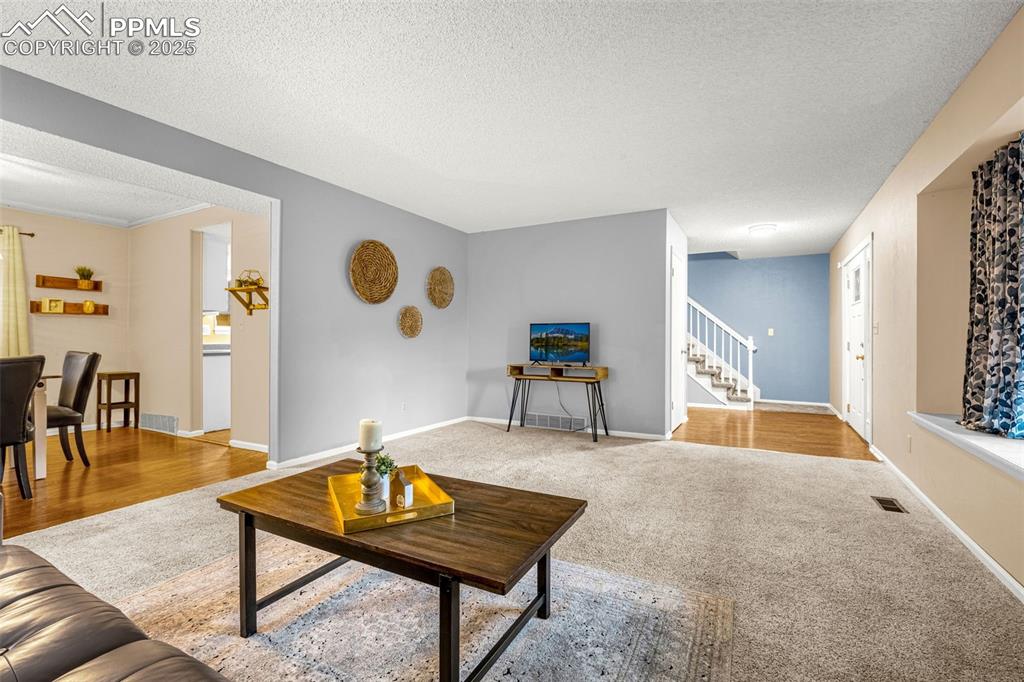 Image 3 of 38: Living room with stairs, carpet, and baseboards