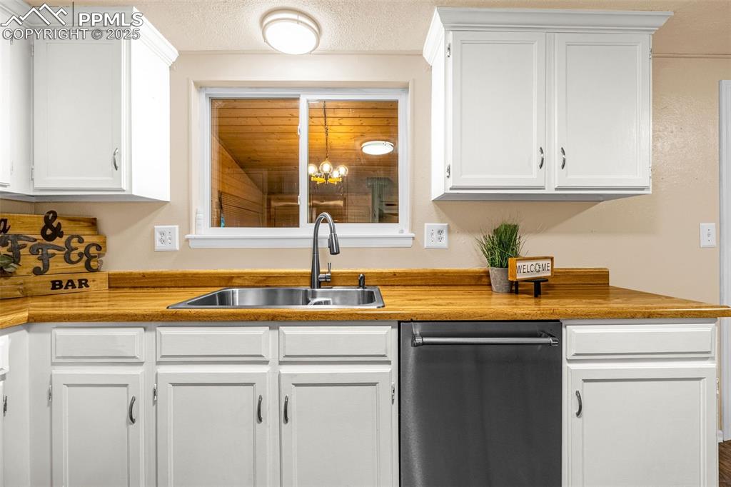 Image 7 of 38: Kitchen featuring a sink, dishwasher, and white cabinetry