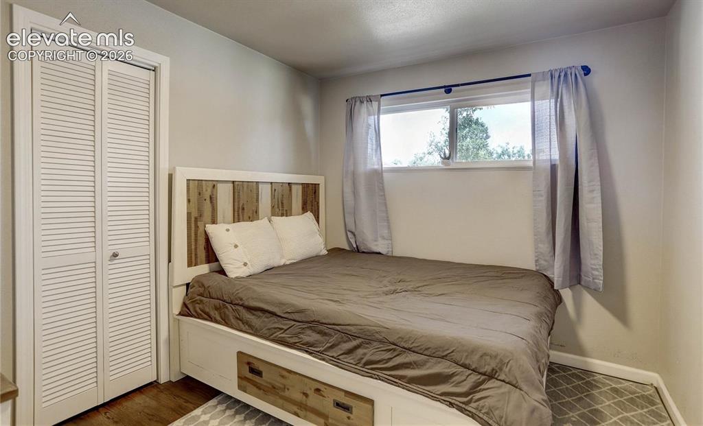 Image 13 of 17: Louvered bi-fold closet doors, neutral wall paint, and wood-finish flooring