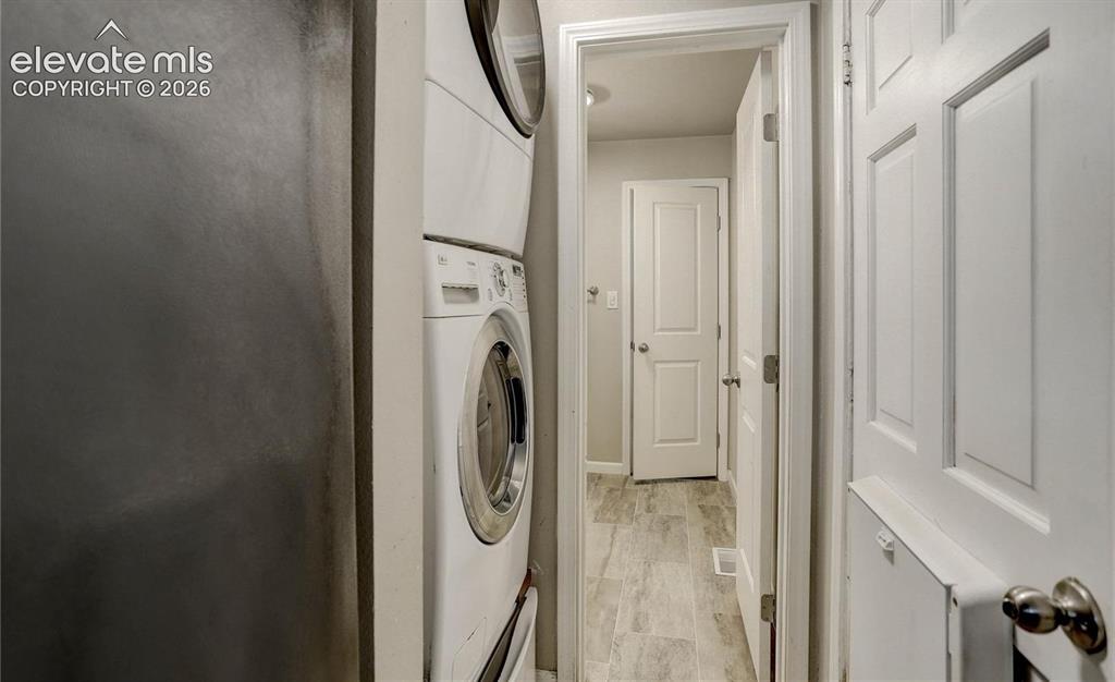 Image 14 of 17: Stackable washer and dryer unit, wood-finish flooring, and white paneled in