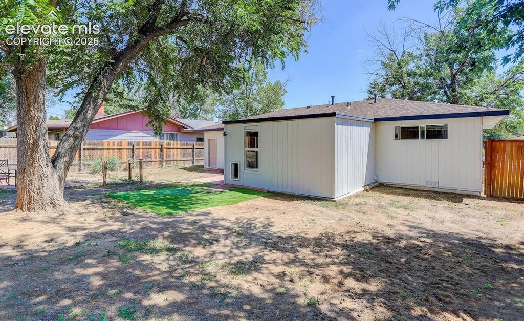 Image 16 of 17: Expansive backyard featuring mature trees, a section of manicured lawn, and
