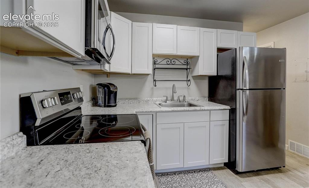 Image 6 of 17: White cabinetry, stainless steel appliances, granite-style countertops, an 