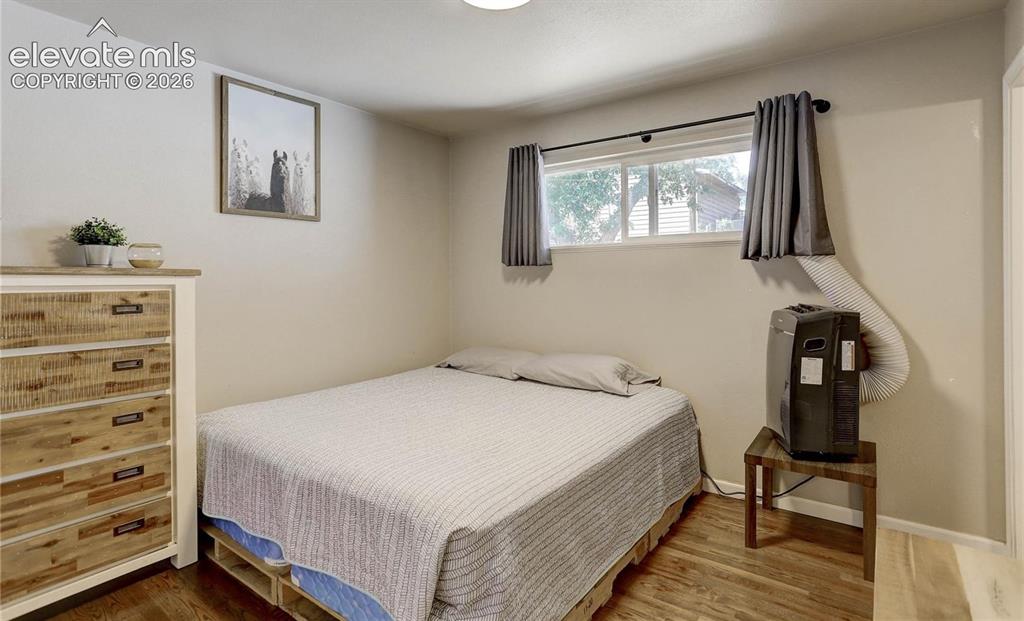 Image 8 of 17: Wood-finish flooring with light-toned walls and a window featuring dark cur