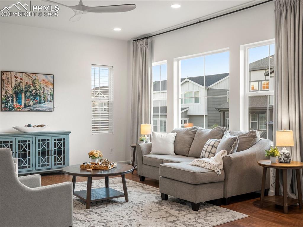 Image 10 of 45: The living area features hardwood floors, a modern ceiling fan, recessed li