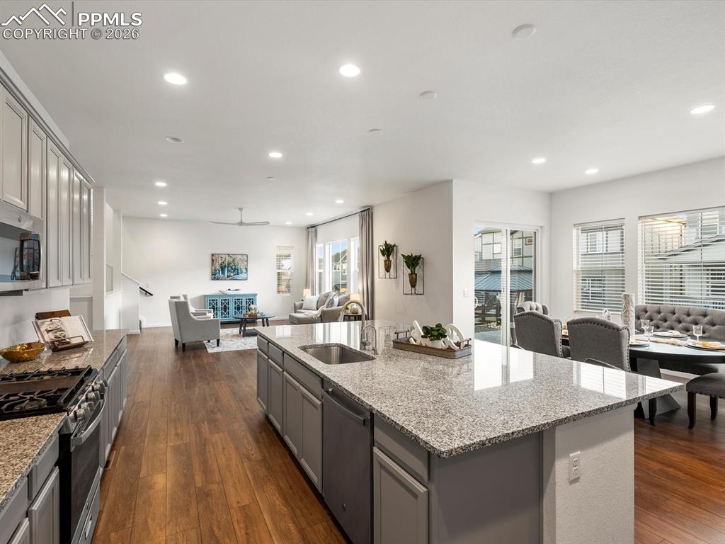 Image 13 of 45: The kitchen features a large island with a sink, granite countertops, and s
