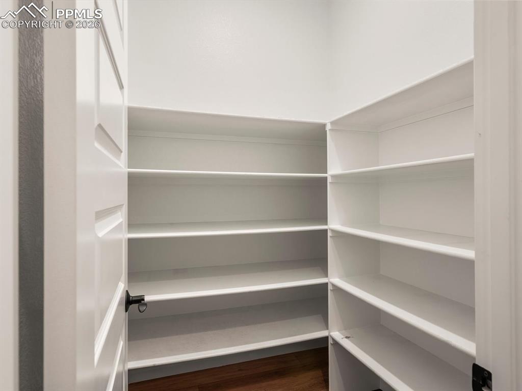 Image 19 of 45: Expansive pantry featuring white shelving, a dark wood floor, and a white p