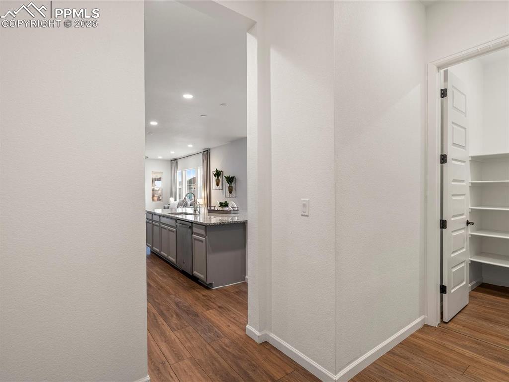 Image 20 of 45: Hallway with hardwood style flooring, leading to a kitchen with an island f
