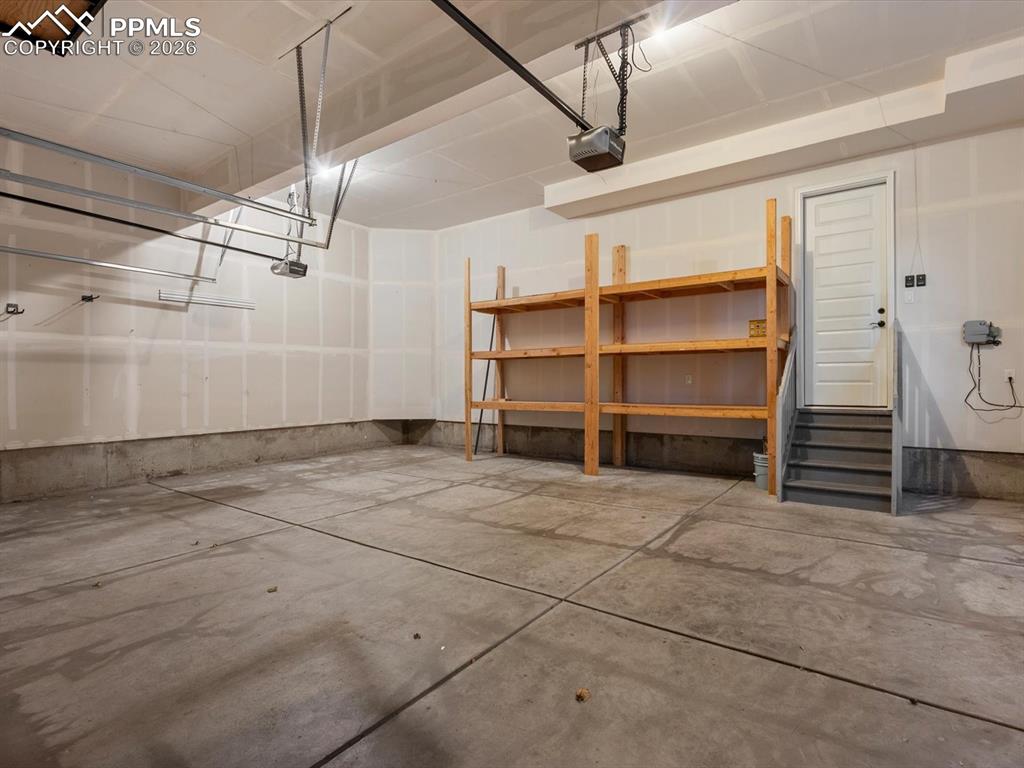 Image 21 of 45: The property features a spacious garage with a concrete floor, built-in woo