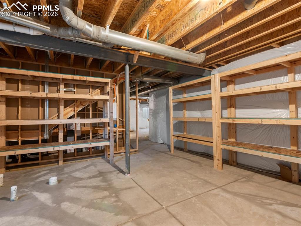 Image 25 of 45: The unfinished basement features exposed wooden joists and beams, a concret