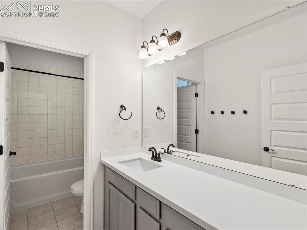 Image 27 of 45: Bathroom featuring a vanity with a white countertop, a mirror, and a bathtu