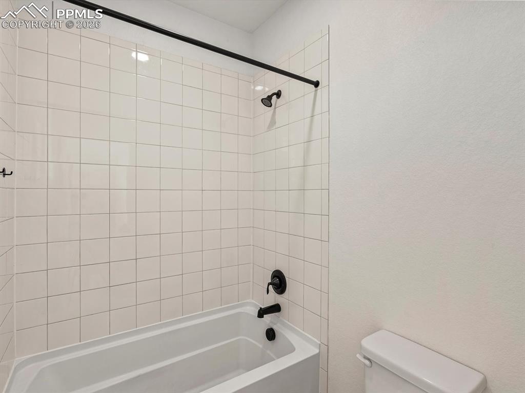 Image 28 of 45: Bathroom featuring a white tiled shower and bathtub combination with matte 
