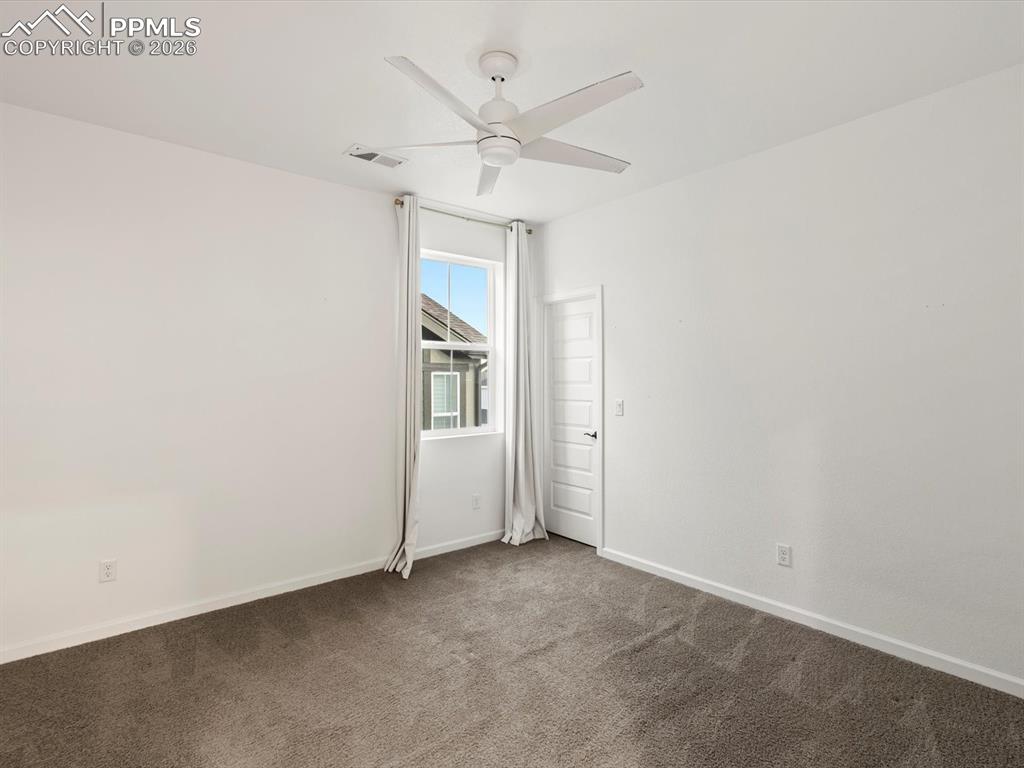 Image 30 of 45: This room features a ceiling fan, carpeted flooring, and a window with whit