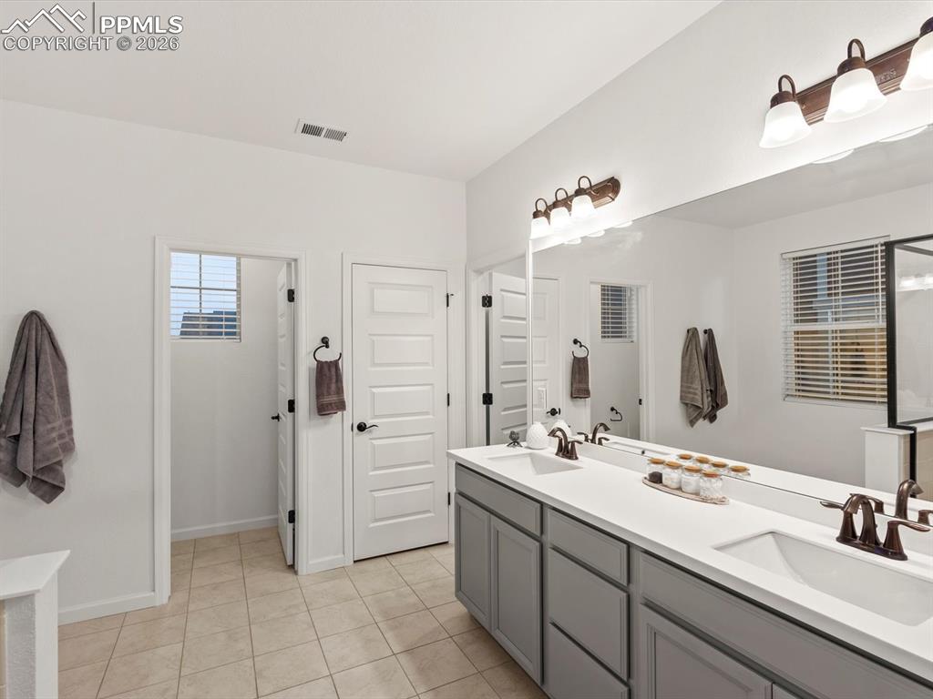 Image 39 of 45: Bathroom featuring a spacious double vanity with light gray cabinetry, whit