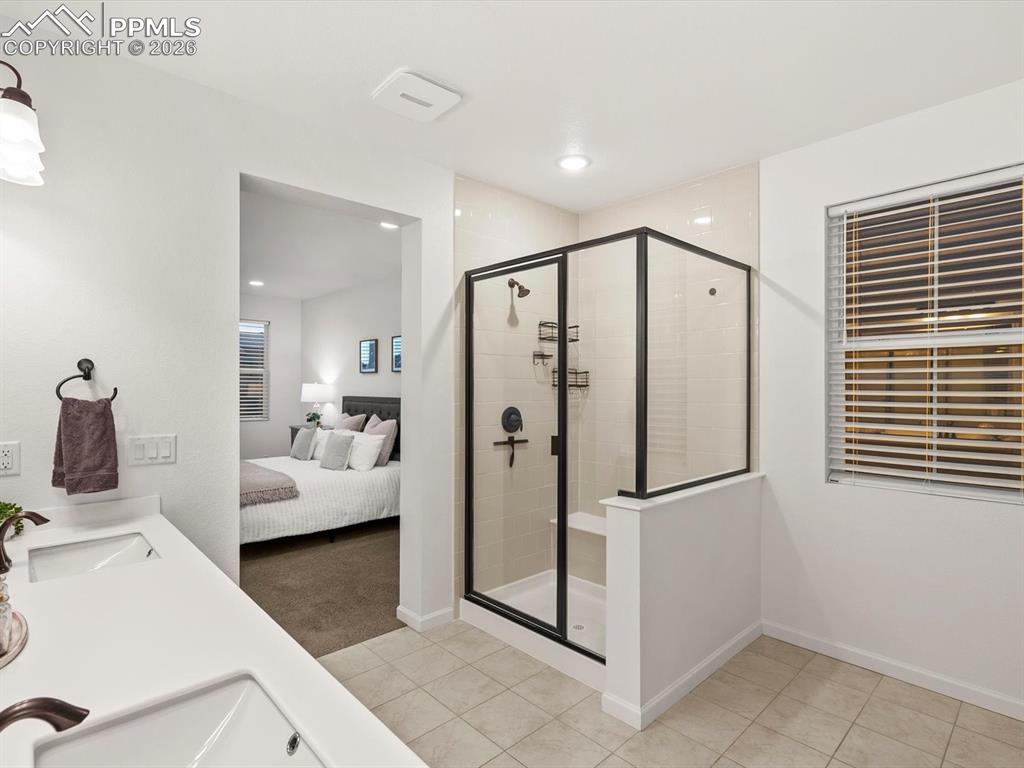 Image 41 of 45: Bathroom featuring a glass-enclosed shower with black trim, a window with b