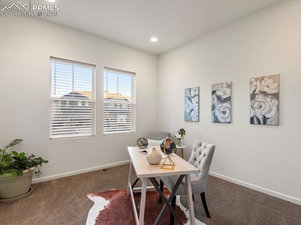 Image 6 of 45: This versatile room features two windows with blinds, carpeted flooring, an