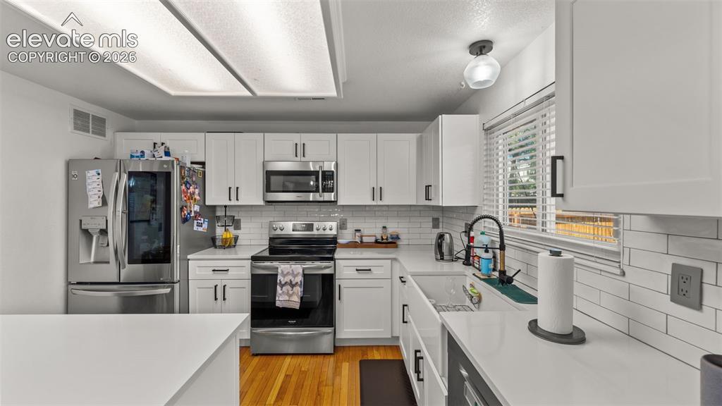 Image 13 of 34: White shaker-style cabinetry with black hardware, subway tile backsplash, w