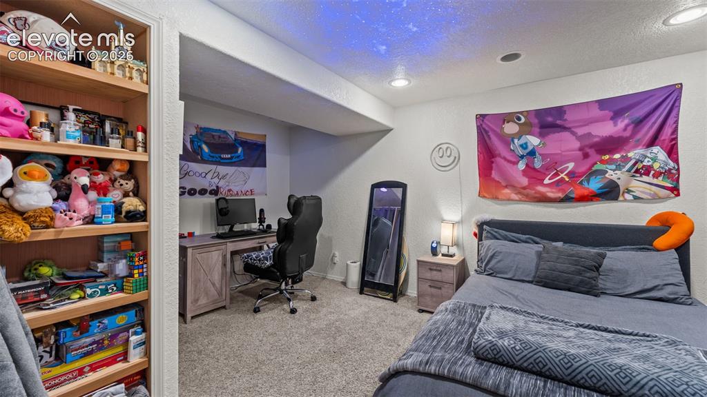 Image 15 of 34: Built-in shelving, recessed lighting, carpeted flooring, and a desk area