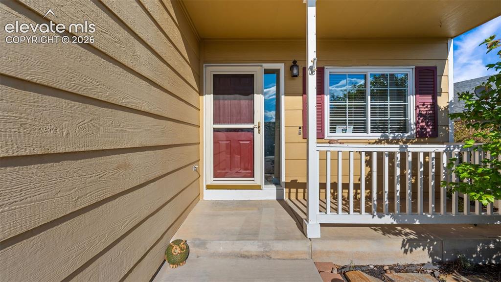 Image 4 of 34: Front entry featuring a red panel door with a screen door, covered porch, a