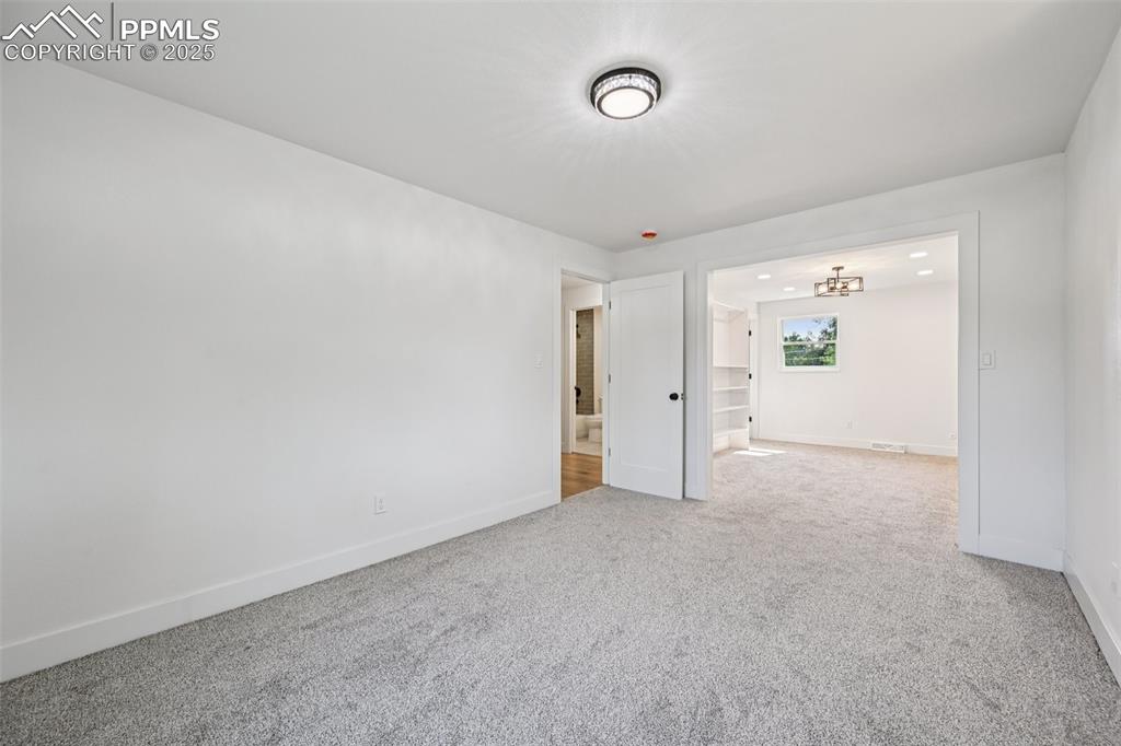 Image 22 of 49: Spare room featuring carpet and a chandelier