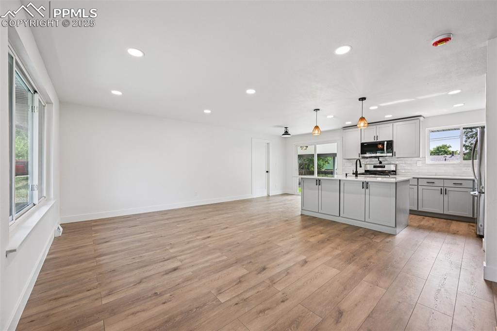 Image 4 of 49: Kitchen with gray cabinets, light wood-type flooring, light countertops, de
