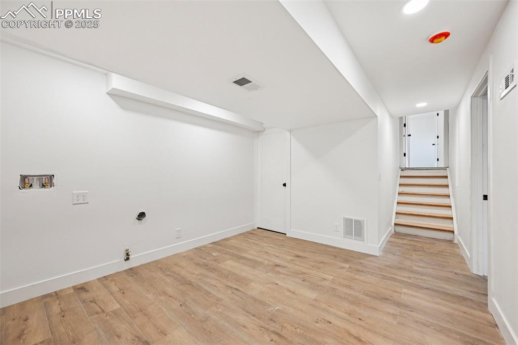 Image 40 of 49: Finished basement with stairs, light wood-style floors, and recessed lighti