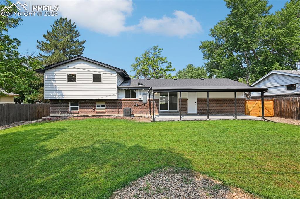 Image 48 of 49: Rear view of house featuring brick siding, a fenced backyard, and a patio