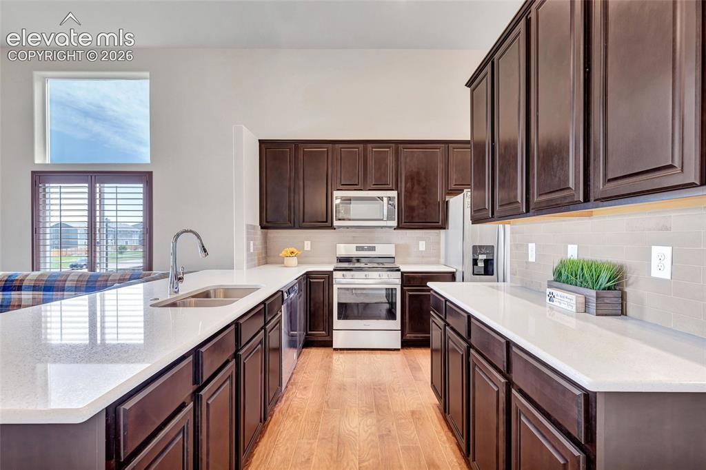 Image 10 of 38: Contemporary kitchen featuring abundant dark wood cabinetry, light-toned co