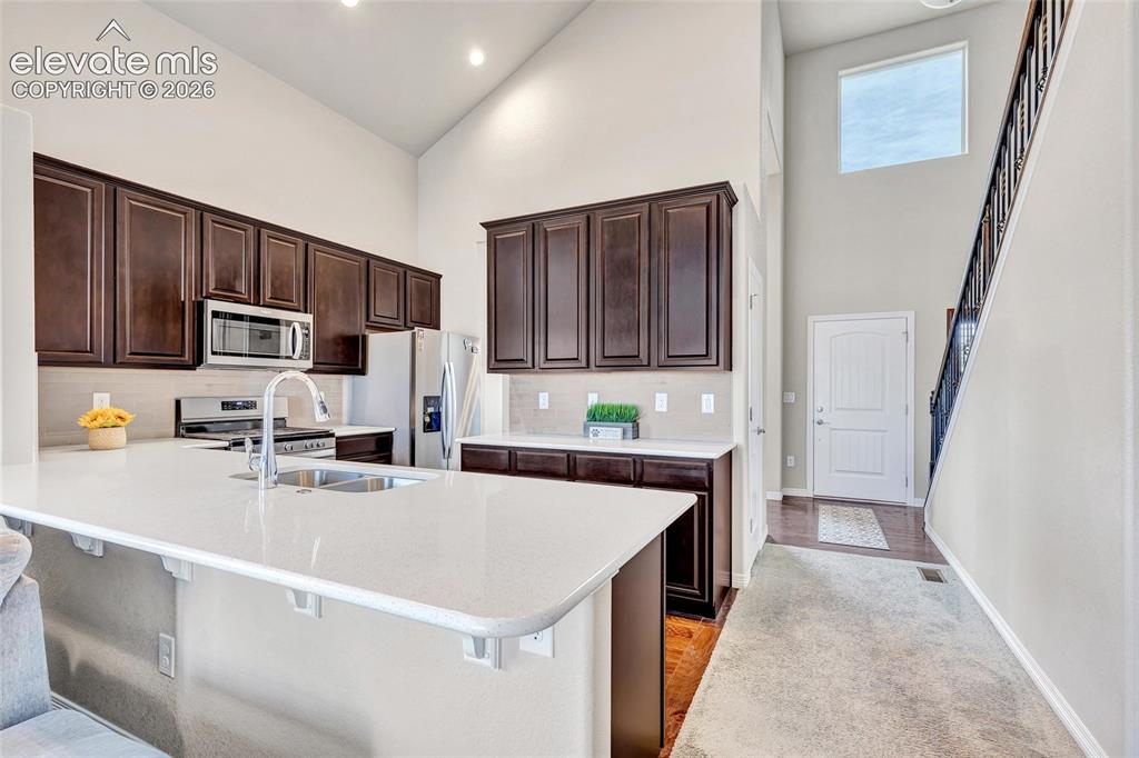Image 11 of 38: Kitchen featuring dark wood cabinetry, stainless steel appliances, a white