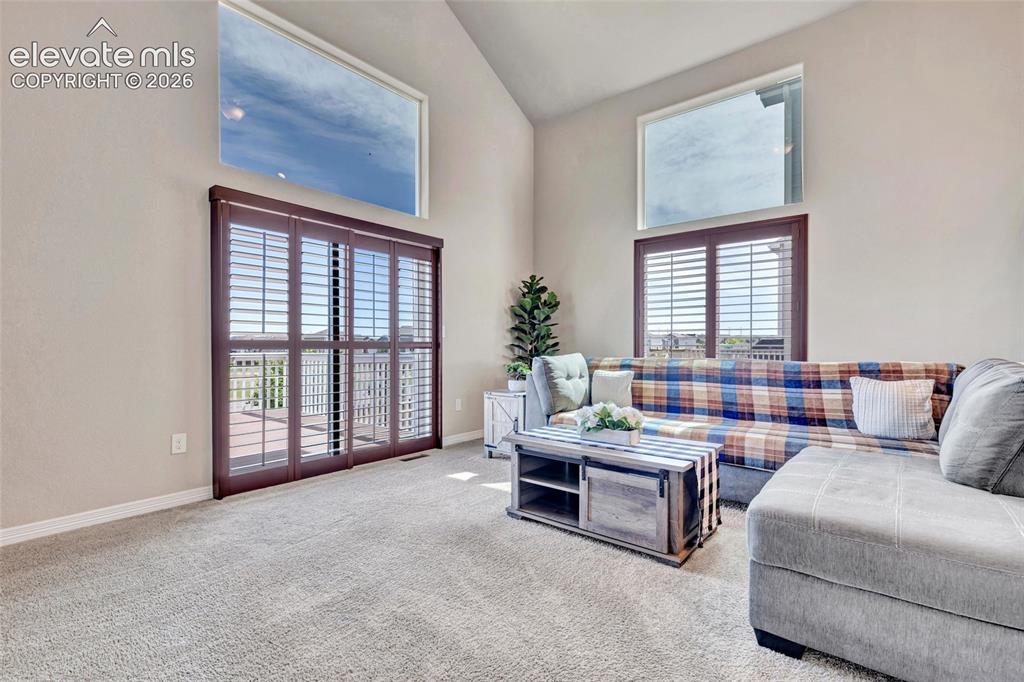 Image 12 of 38: Spacious living area featuring vaulted ceilings, light-toned carpeting, and