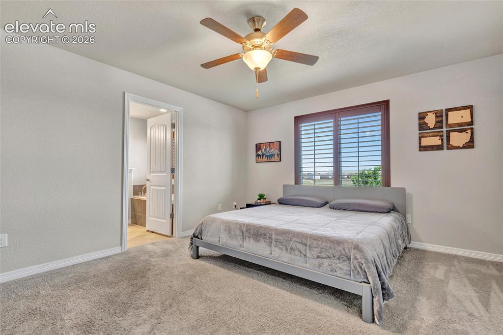 Image 18 of 38: Carpeted bedroom featuring a ceiling fan with integrated lighting, wood-fin