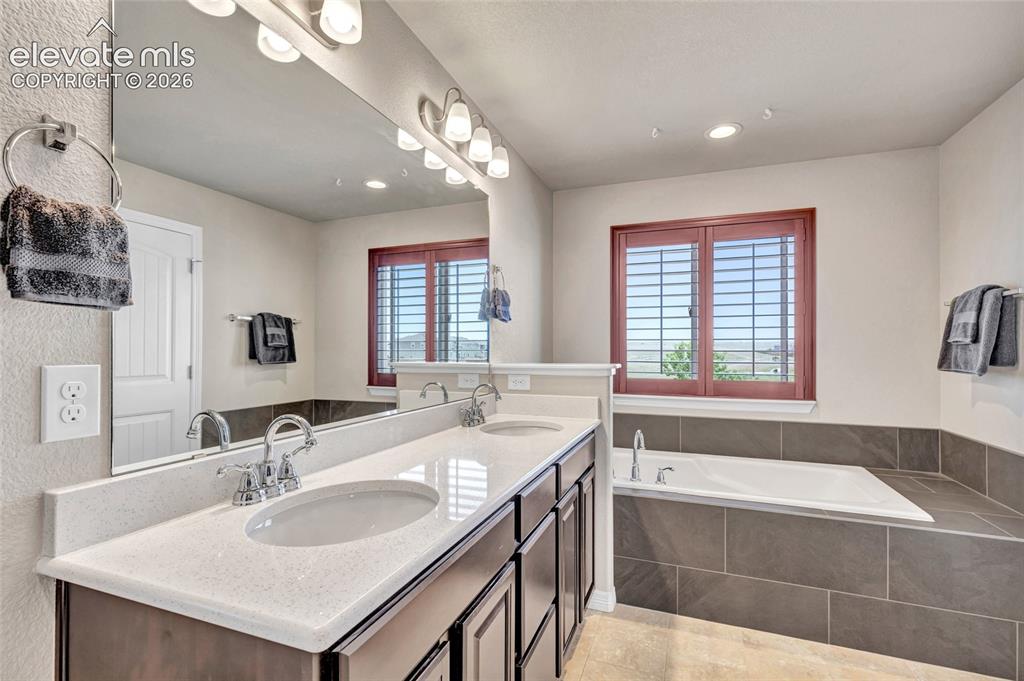 Image 19 of 38: Spacious bathroom featuring a dual vanity with light-toned countertops, chr