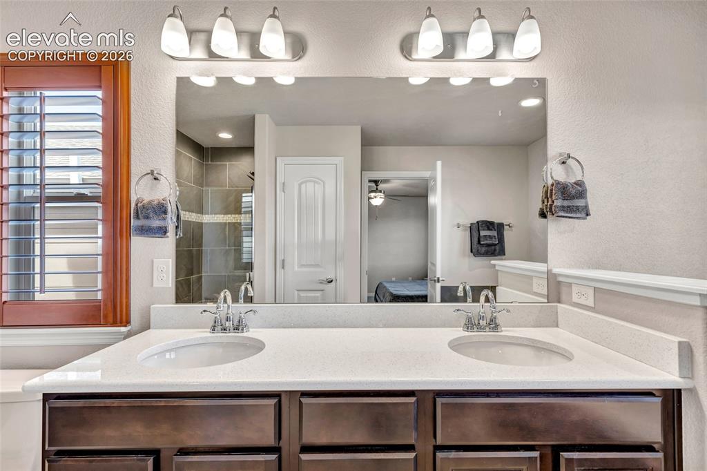 Image 21 of 38: Dual vanity with white solid-surface countertops, integrated sinks, and chr