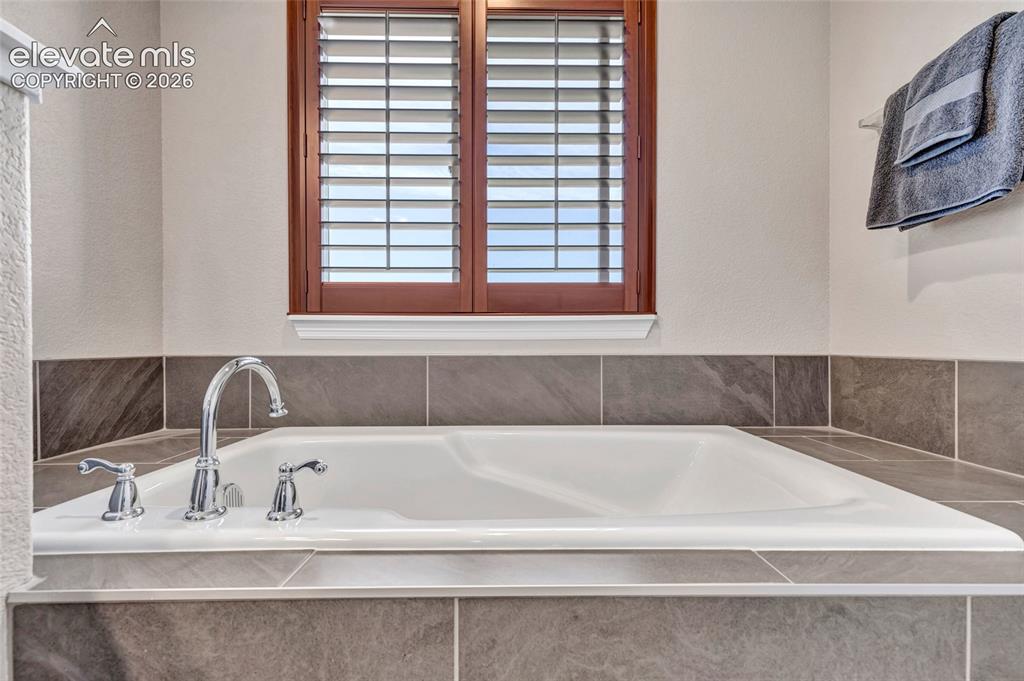 Image 22 of 38: Soaking tub with chrome fixtures and surrounding tilework