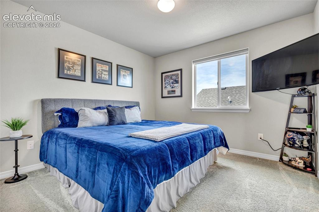 Image 25 of 38: Carpeted bedroom featuring a large window, light gray walls, white baseboar