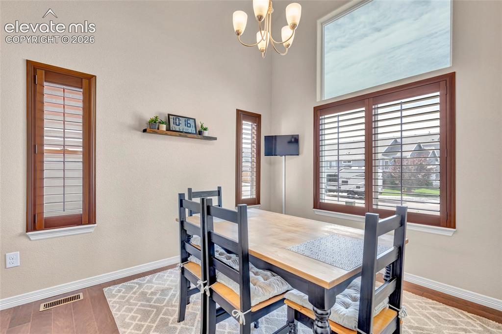 Image 5 of 38: Dining area featuring high ceilings, wood-finish flooring, and a decorative