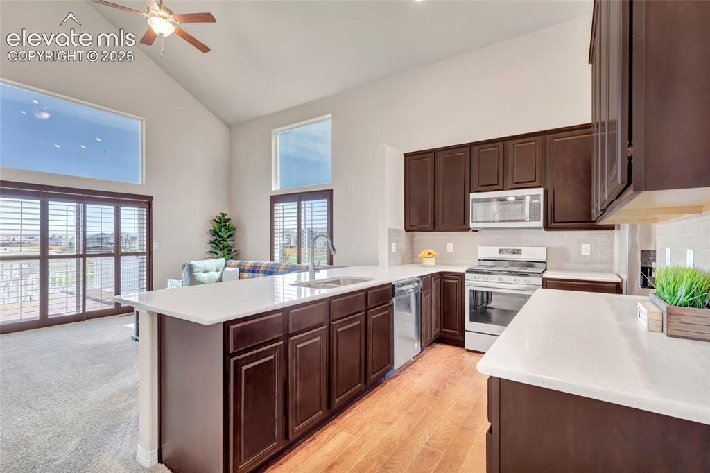 Image 6 of 38: Open-concept kitchen featuring wood-finish flooring, white countertops, dar