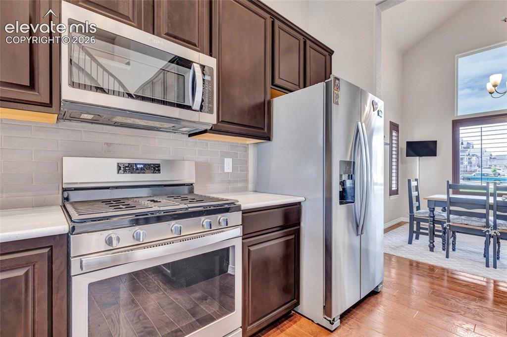 Image 9 of 38: Kitchen featuring stainless steel appliances, dark wood cabinetry, white co