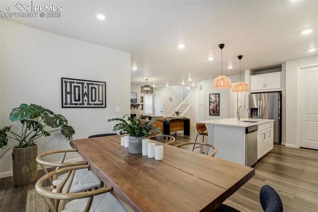 Image 13 of 50: Dining room with wood-style floors, stairway, recessed lighting, and a chan